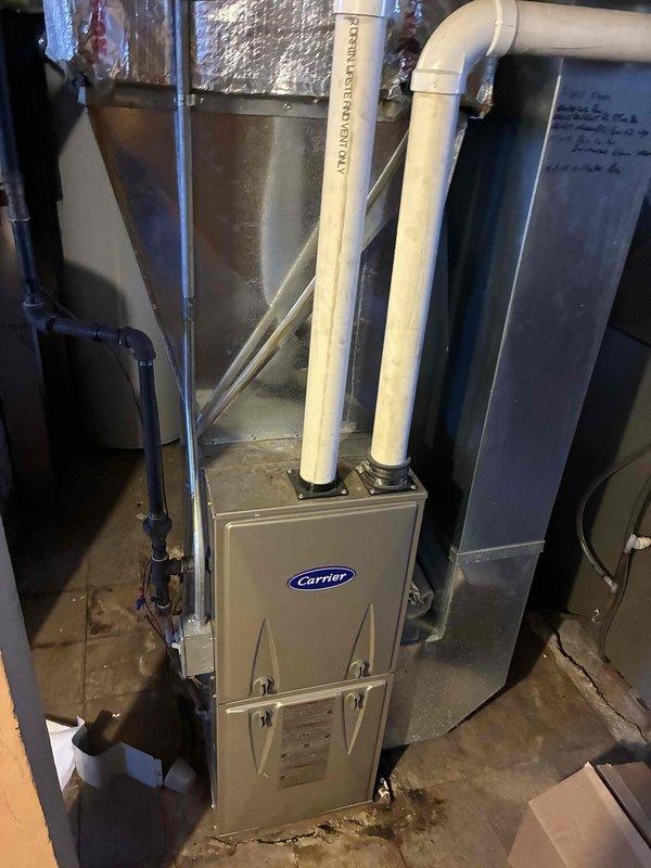 Performed routine maintenance on Carrier furnace system located in basement utility area. Inspected PVC intake/exhaust venting pipes and confirmed proper installation. Checked condensate drain lines and noted minor moisture staining around unit base which was addressed during service.