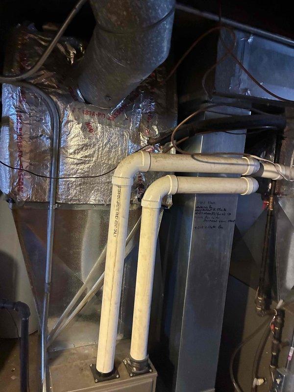 Performed routine maintenance on Carrier furnace system located in basement utility area. Inspected PVC intake/exhaust venting pipes and confirmed proper installation. Checked condensate drain lines and noted minor moisture staining around unit base which was addressed during service.
