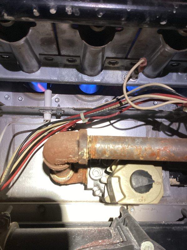 Responded to no heat call for unit under 10 years old. Upon inspection, found significant rust and debris below the furnace. Investigation revealed severely corroded copper piping in the burner assembly with active blue flames present. Cleaned accumulated rust particles from the area, replaced deteriorated copper gas line assembly, and verified proper burner operation before completing service.