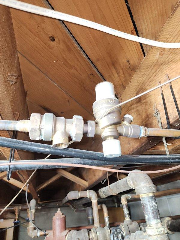 Performed inspection and service on plumbing infrastructure in utility area. Identified corrosion on copper piping connection to Caleffi brass valve/regulator assembly. Documented condition of PVC pipe junctions and metal fixtures in crawlspace/ceiling area for future maintenance recommendations.
