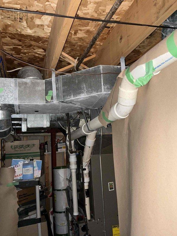 Completed replacement of an aging HVAC system in the attic/crawl space area, installing new air handling unit with properly insulated ductwork and PVC condensate drain lines. System installation included connecting all necessary junction boxes, securing proper electrical connections, and ensuring proper ventilation through the existing rectangular sheet metal ducting in the basement/utility area.