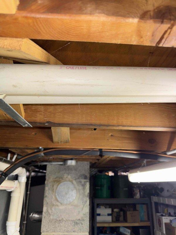 Performed routine tune-up service on HVAC system in basement utility room. Inspected ceiling-mounted ductwork and accessible components. Observed PVC Coreline pipe installation running between joists, which appears to be properly secured and in good condition. No immediate concerns identified with visible system components.