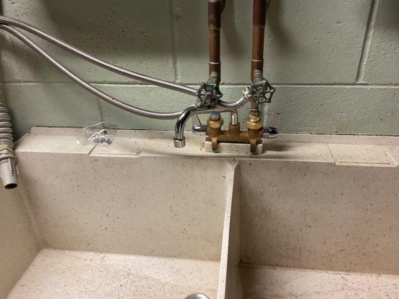 Completed installation of a double-basin utility sink with new supply lines in basement/utility area. Connected copper supply lines to brass mixing valve and installed chrome faucet assembly. Verified proper operation with no leaks and confirmed all connections were secure.