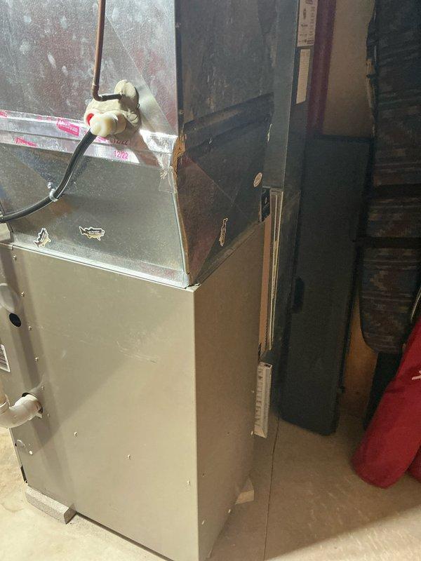 Completed installation of a Payne furnace unit in utility/mechanical room, replacing aging HVAC system. New installation includes properly connected PVC ventilation pipes, sealed ductwork connections with metallic tape, and verified operational status as indicated by system indicator light.