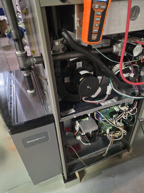 Completed Honeywell Home furnace installation with proper pressure testing using Klein Tools ET100 digital pressure meter (confirmed reading of 1.78). Installation included proper connection of blower motor assembly, electrical wiring, and PVC ventilation system. Final diagnostic checks confirmed all systems functioning within manufacturer specifications.