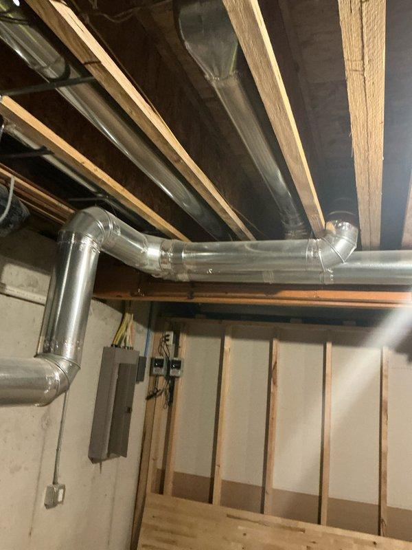 Conducted comprehensive inspection of existing HVAC system, focusing on ductwork in basement utility area. Current system maintains indoor temperature at 66°F (heating mode) but evaluation revealed need for full system replacement. Documented condition of metal ductwork, connections, and existing Venmar ventilation controller alongside the primary thermostat for integration considerations in the replacement proposal.