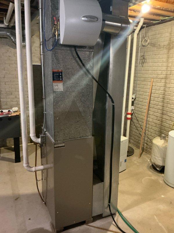 Completed replacement of residential HVAC system including installation of new furnace with integrated humidifier in basement utility room and outdoor heat pump/AC unit mounted on concrete pad. System features PVC venting, proper electrical connections with disconnect box, and complete integration with existing ductwork and utility connections.