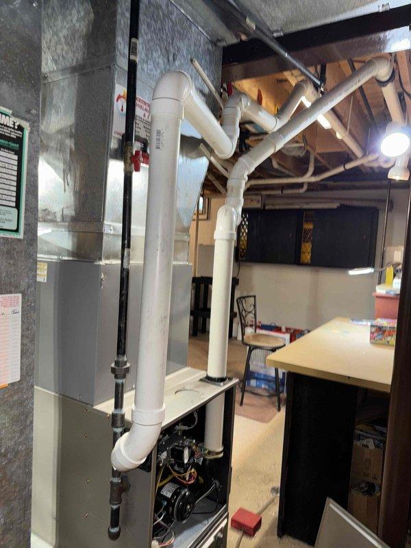 Performed annual maintenance tune-up on the residential gas furnace system located in the basement utility room. Inspected internal components after removing access panel, checked all electrical connections and wiring for proper operation. Examined the PVC ventilation system for proper installation and signs of leakage; all connections appear secure with no visible issues detected.