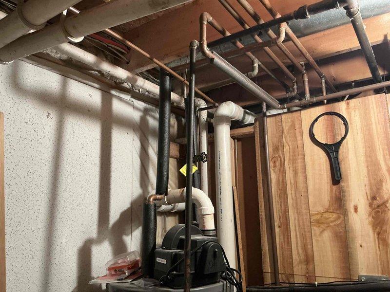 Conducted inspection of existing home heating system located in basement utility area. Verified installation of Tempstar/Heil furnace with proper metal ductwork connections and PVC intake/exhaust venting secured with appropriate strapping. Examined surrounding plumbing infrastructure including copper and PVC piping systems for potential integration issues. System appears properly installed with all components functional.