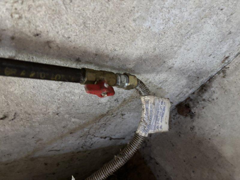 Conducted inspection of aging copper water supply lines exhibiting significant oxidation and corrosion. Identified brass fittings with tarnishing and examined red valve handles and flexible metal hoses for functionality. Evaluated black supply line with brass fitting and spiral metal protective covering, noting potential replacement requirements due to deterioration around connection points.