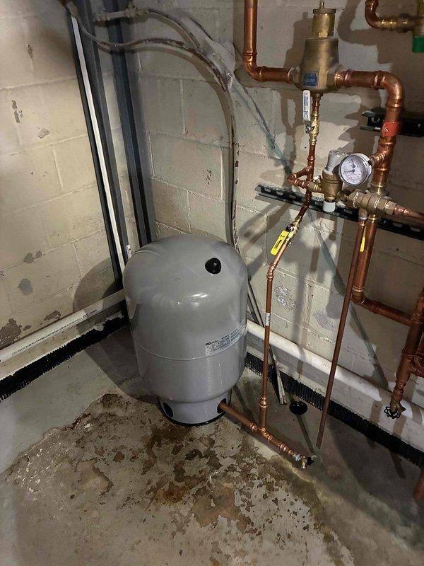 Performed preventative maintenance on NTI boiler system showing operating temperature of 179°F. Inspected expansion tank, pressure gauge, and associated copper piping network for proper function. System appears to be operating within normal parameters with minor moisture noted near floor drain that will require monitoring.