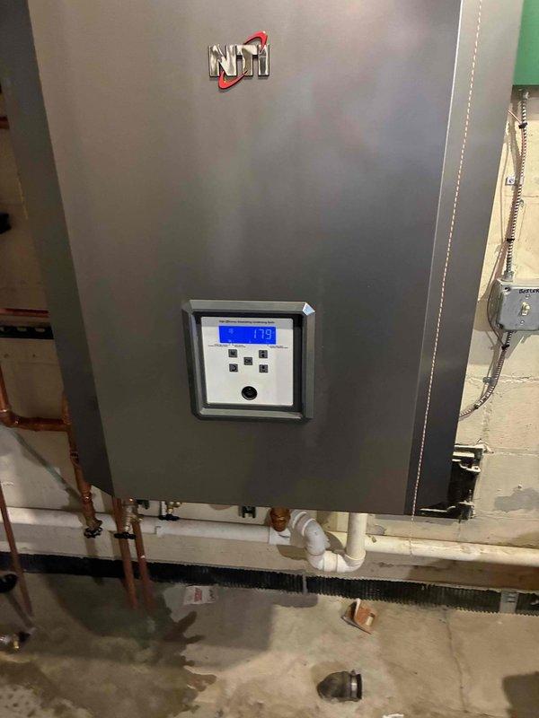 Performed preventative maintenance on NTI boiler system showing operating temperature of 179°F. Inspected expansion tank, pressure gauge, and associated copper piping network for proper function. System appears to be operating within normal parameters with minor moisture noted near floor drain that will require monitoring.