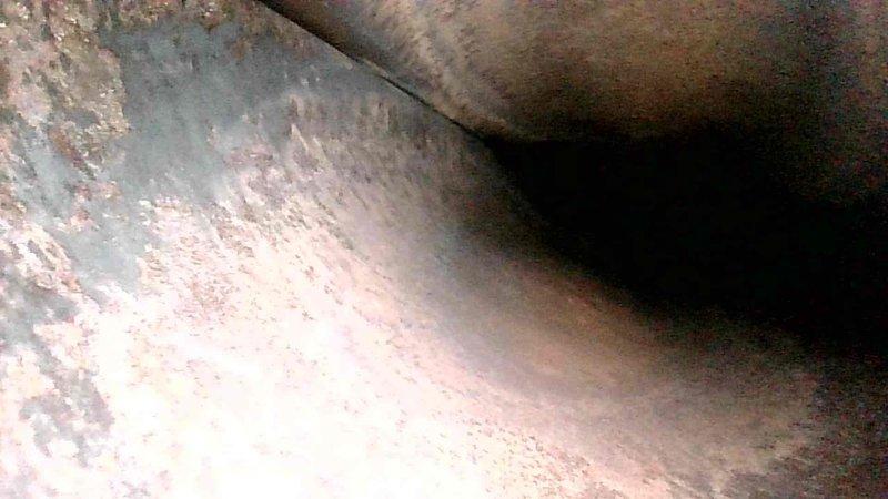 Performed routine maintenance tune-up on HVAC system, including inspection of ductwork. Interior duct examination revealed significant buildup of dust and potential soot accumulation on surfaces. Photos documented the condition of ductwork showing textured, discolored interior surfaces with possible mineral deposits and corrosion that may affect system efficiency.