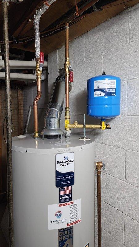 Completed installation of a Bradford White residential water heater in basement utility area. Installation included proper connection of copper piping, installation of expansion tank with control valves, and connection of metallic vent pipes. All components were professionally installed and tested to ensure proper operation.