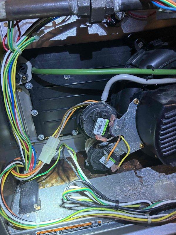 Performed diagnostic inspection on HVAC system revealing internal wiring issues. Accessed unit control panel, examined electrical components, and identified faulty connections within the wire bundles (yellow, green, blue, red, white). Restored proper functionality by reconnecting and securing loose connections to motor assembly.