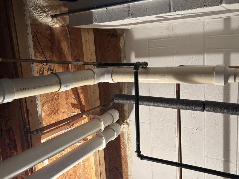 Conducted comprehensive inspection of residential plumbing system. Verified proper installation of PVC supply lines and drainage pipes in basement utility area. Examined A.O. Smith water heater and adjacent filtration unit, confirming all copper connections and valves were functioning correctly with no leaks detected.