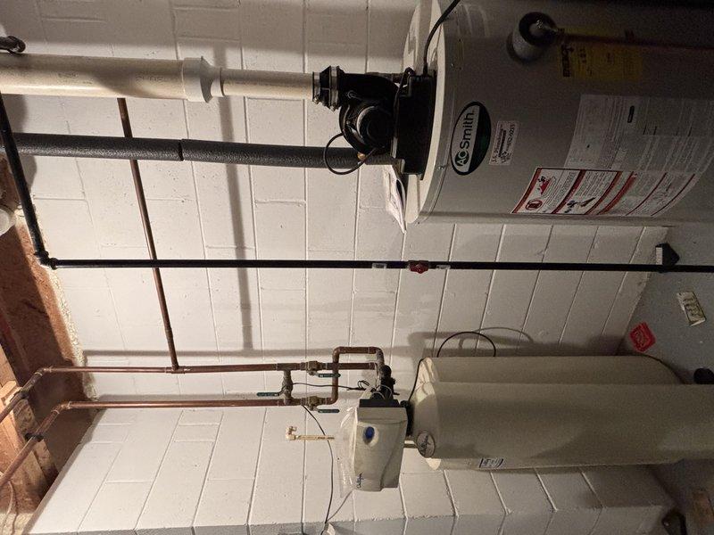 Conducted comprehensive inspection of residential plumbing system. Verified proper installation of PVC supply lines and drainage pipes in basement utility area. Examined A.O. Smith water heater and adjacent filtration unit, confirming all copper connections and valves were functioning correctly with no leaks detected.