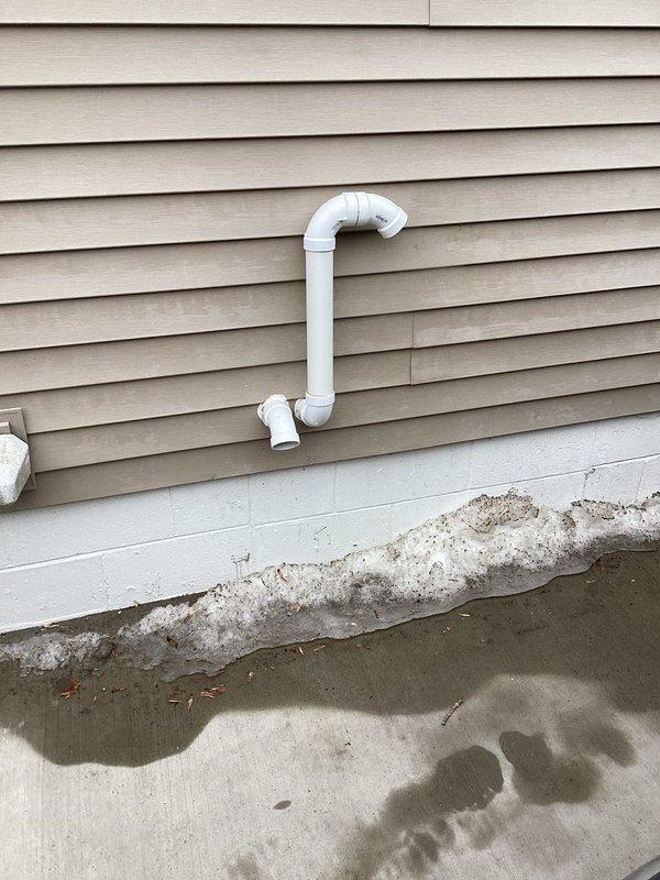 Completed installation of a new furnace system with digital programmable thermostat mounted on interior wall. Installed proper PVC venting through exterior siding with P-trap configuration for condensate drainage. All components tested and functioning correctly with temperature control set to 70°F.