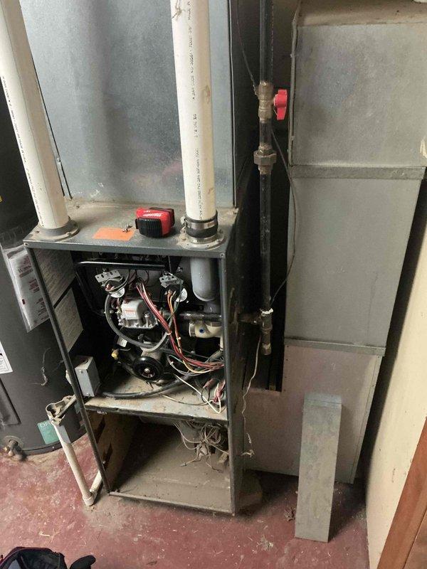 Completed assessment of aging heating system, revealing exposed control board and electrical components requiring attention. Documented furnace installation with PVC ventilation pipes and noted red shut-off valves that need maintenance. Recommended replacement of the existing unit due to observed wear and potential efficiency issues with the current HVAC configuration in the utility area.