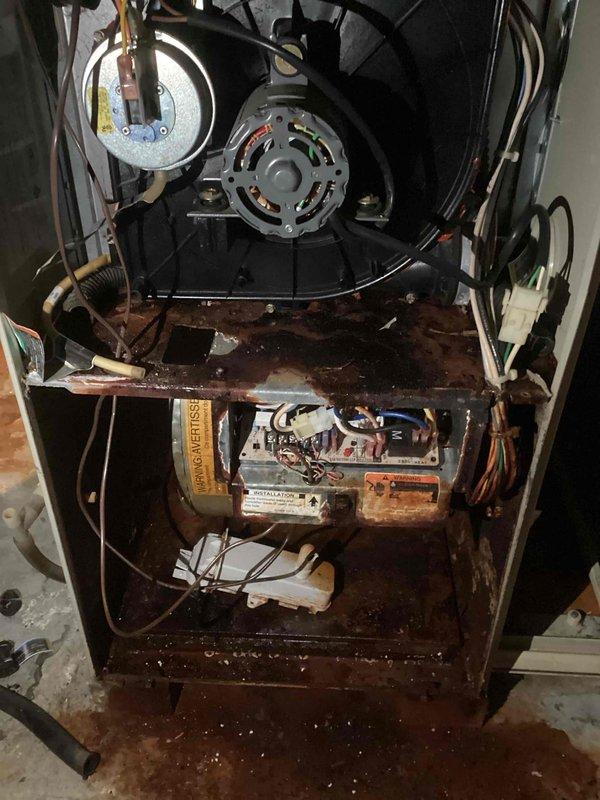 Performed inspection of furnace revealing extensive corrosion and rust damage throughout the interior cabinet and components. Documented severe oxidation on the bottom panel, control board area, and motor assembly mounting points. Unit requires immediate replacement due to compromised structural integrity and safety concerns.