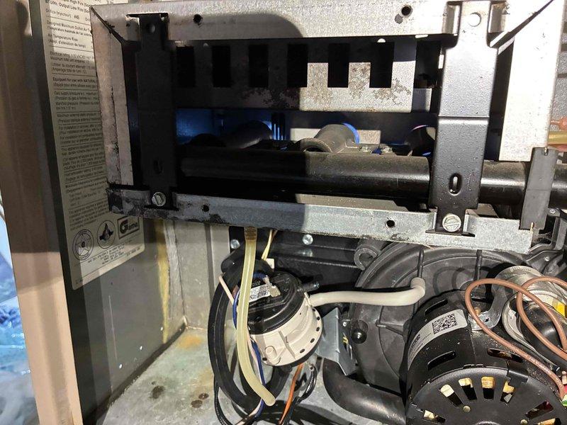 Performed inspection of furnace system located in basement utility area. Accessed interior components of the blower assembly to examine motor, electrical connections, and ventilation system. Visual inspection revealed normal operational condition of the furnace with no apparent mechanical or electrical issues identified.