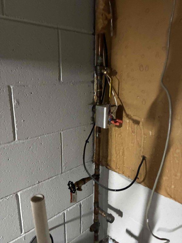 Performed routine tune-up on HVAC system in utility area, inspecting exposed ductwork and piping. Identified minor deterioration of insulation on several pipes and noted previous water damage on wall near control module. System is operational but showing signs of age with some components requiring future attention.