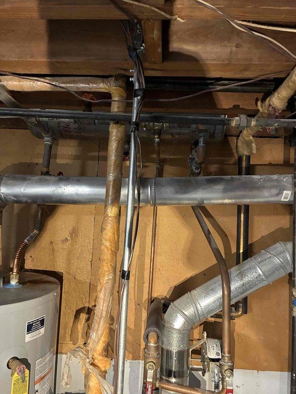 Performed routine tune-up on HVAC system in utility area, inspecting exposed ductwork and piping. Identified minor deterioration of insulation on several pipes and noted previous water damage on wall near control module. System is operational but showing signs of age with some components requiring future attention.