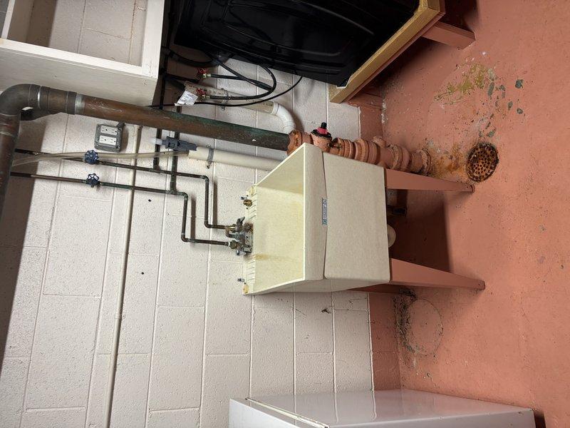 Assessed and corrected significant corrosion on copper drain pipe servicing utility sink in basement, which had caused water damage and potential mold development on surrounding wall areas. Additionally, inspected and serviced three mint green water circulation pumps on the hydronic heating system, confirming proper operation of the labeled zones including "Family Room" circuit.