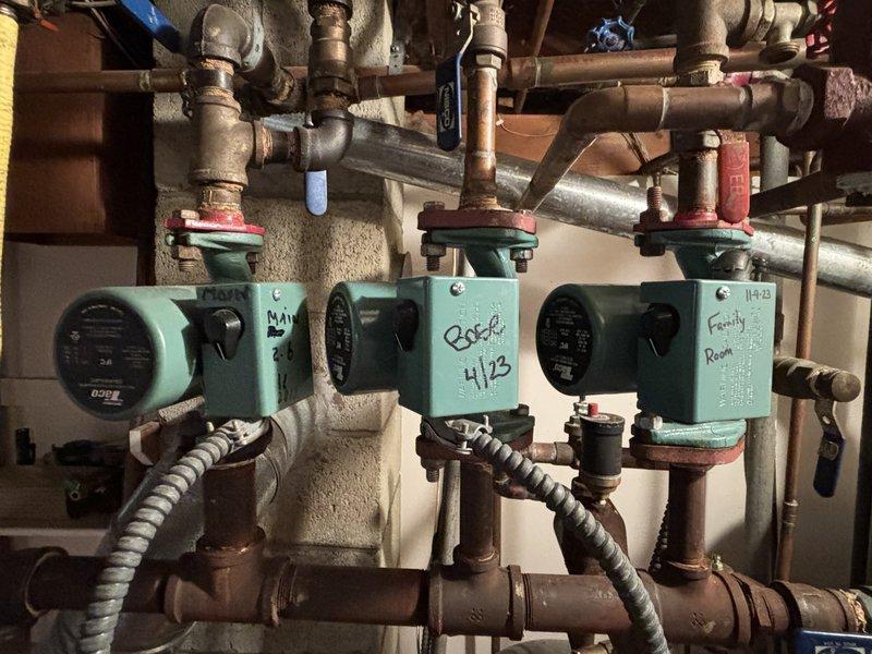 Assessed and corrected significant corrosion on copper drain pipe servicing utility sink in basement, which had caused water damage and potential mold development on surrounding wall areas. Additionally, inspected and serviced three mint green water circulation pumps on the hydronic heating system, confirming proper operation of the labeled zones including "Family Room" circuit.