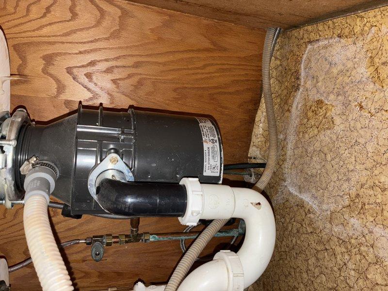 Successfully installed new garbage disposal unit under kitchen sink. Completed proper mounting of the black disposal motor to sink flange and connected all white PVC drain pipes with appropriate fittings. Ensured secure connections with rubber gasket and verified system functionality before completing service.