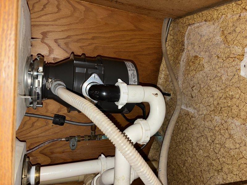 Successfully installed new garbage disposal unit under kitchen sink. Completed proper mounting of the black disposal motor to sink flange and connected all white PVC drain pipes with appropriate fittings. Ensured secure connections with rubber gasket and verified system functionality before completing service.