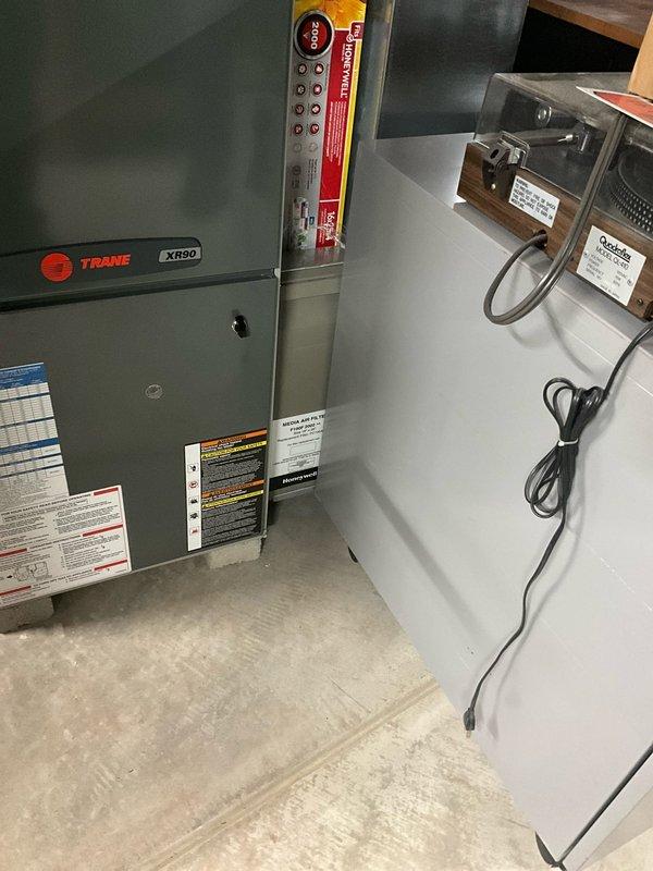 Completed HVAC system replacement in customer's utility room, installing a new Trane XR80 furnace with proper PVC venting secured to ceiling joists. System includes digital thermostat/control panel mounted adjacent to the furnace unit with all electrical connections properly wired and tested for optimal performance.