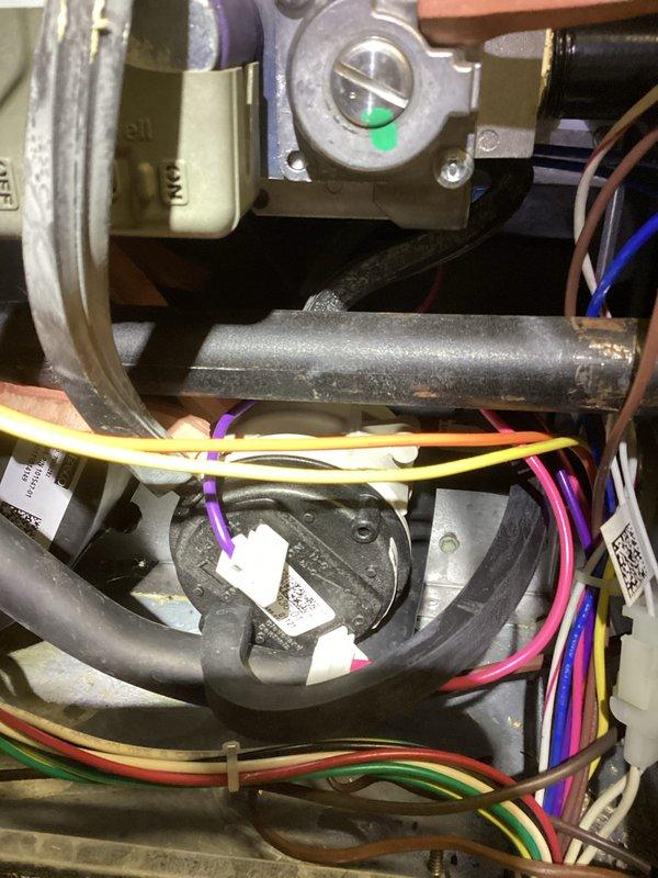 Performed diagnostic assessment on 10+ year old heating system not producing heat. Inspected control board and wiring connections in furnace, finding loose connections and slight corrosion on the main circuit board terminals. Reconnected and secured all wiring harnesses, particularly focusing on the multicolored control wires connected to the circular component. Cleaned corrosion from terminals and verified proper voltage to the ignition system. System now operating correctly with consistent flame ignition and proper heating cycle.