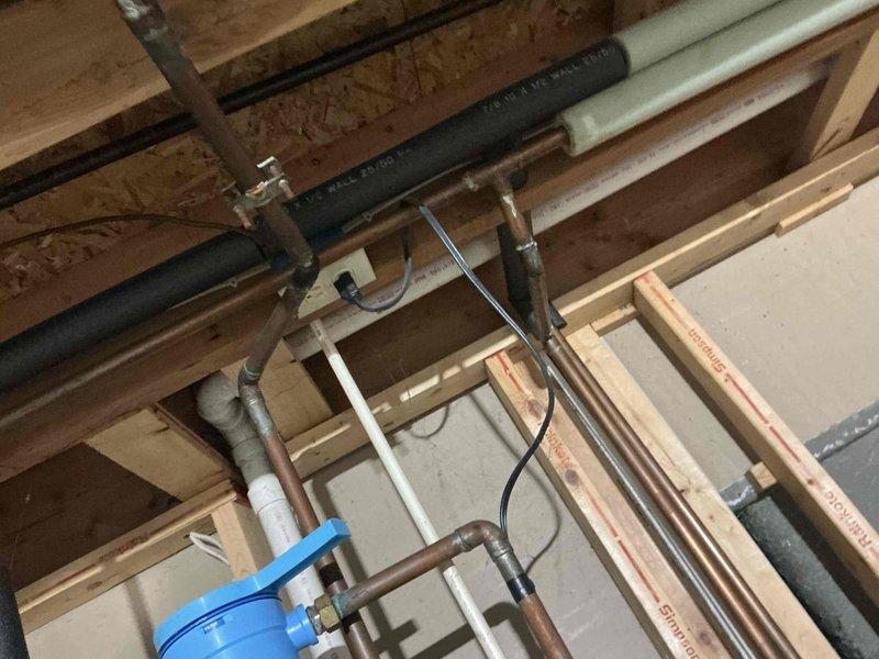 Performed comprehensive inspection of residential HVAC and plumbing systems in unfinished utility area, focusing on IAQ improvement opportunities. Documented existing installation including PVC drainage pipes, copper supply lines, and black insulated HVAC ductwork. Identified areas requiring modification to optimize indoor air quality performance with current system configuration.