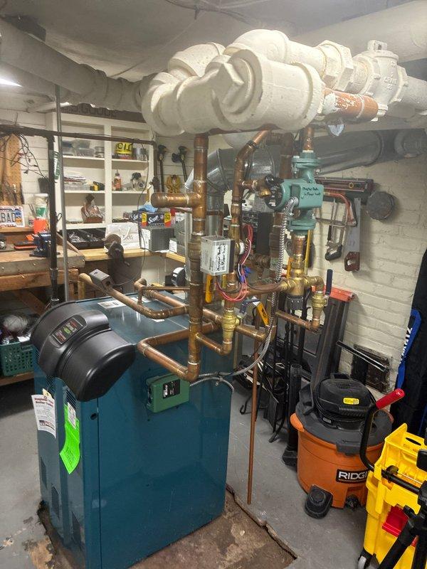 Conducted comprehensive inspection of existing blue-green boiler system in utility room basement. Documented extensive copper piping network, brass valves, and circulation pump. Evaluated connection points to water heater and PVC drainage/ventilation components. Photos taken for documentation and future reference.