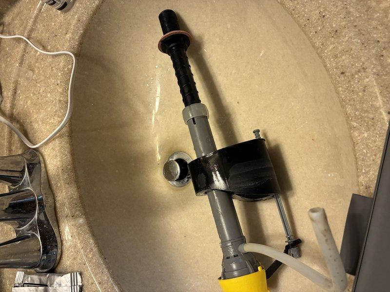 Replaced drain assembly in bathroom sink, including installation of new PVC pipe with rubber seal and threaded mounting components. Observed mineral deposits on sink surface but confirmed proper drainage functionality after installation.