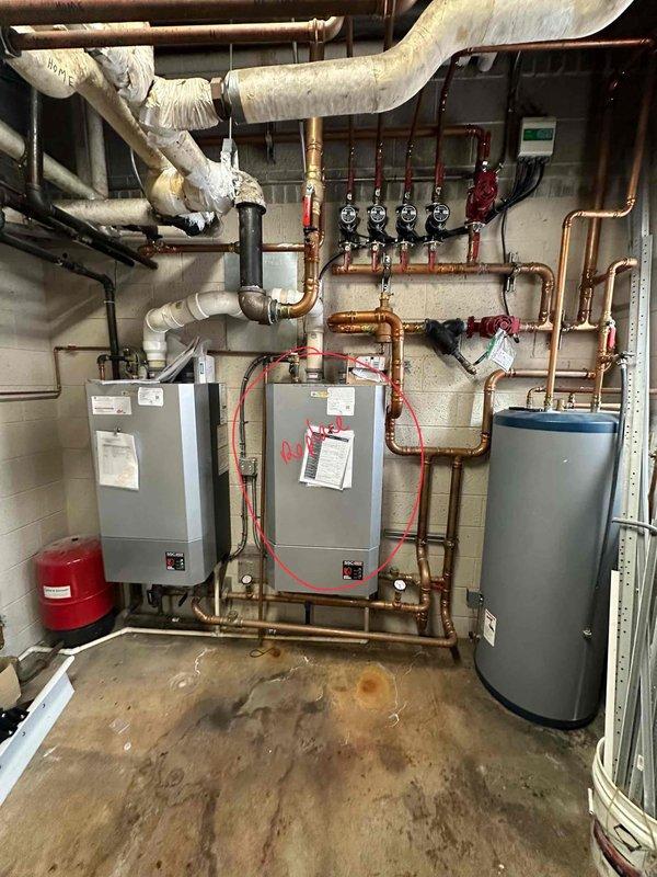 Conducted comprehensive assessment of existing dual wall-mounted boiler system with associated copper piping network and expansion tank. Documented significant water damage and mineral deposits on concrete floor, indicating potential previous leakage issues. Inspection revealed complex plumbing configuration with multiple control valves, pressure gauges, and insulated pipes connecting to cylindrical storage tank, requiring evaluation for system optimization or replacement.
