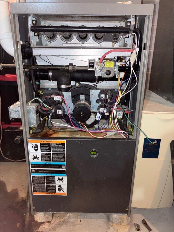 Responded to no heat call for 10+ year old furnace system. Upon inspection, found significant water leak from failed condensate drain causing water accumulation on basement floor. Removed front panel to examine internal components and discovered the blower motor was not operating due to water damage. Installed new motor assembly, cleaned water damage, and restored proper drainage pathway. System tested operational with normal heat output following repair.