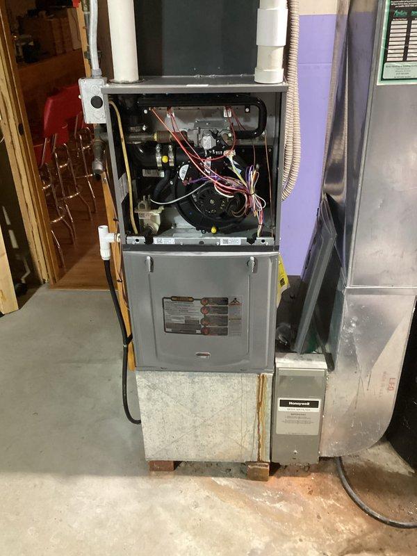 Performed comprehensive tune-up on residential HVAC system, focusing on furnace inspection in basement utility area. Examined exposed ductwork and PVC venting connections for proper installation and integrity. Inspected furnace internal components including wiring array and Honeywell control box, verifying proper electrical connections and operational status.