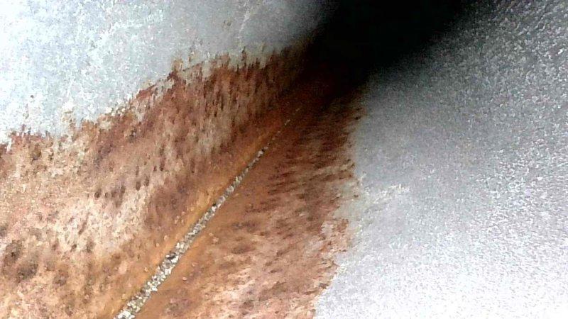 Performed routine HVAC tune-up and identified significant corrosion and rust formation along metal seams in the unit. Documented extensive discoloration and deterioration at critical junction points that may indicate moisture intrusion or ongoing water damage requiring attention in the near future.