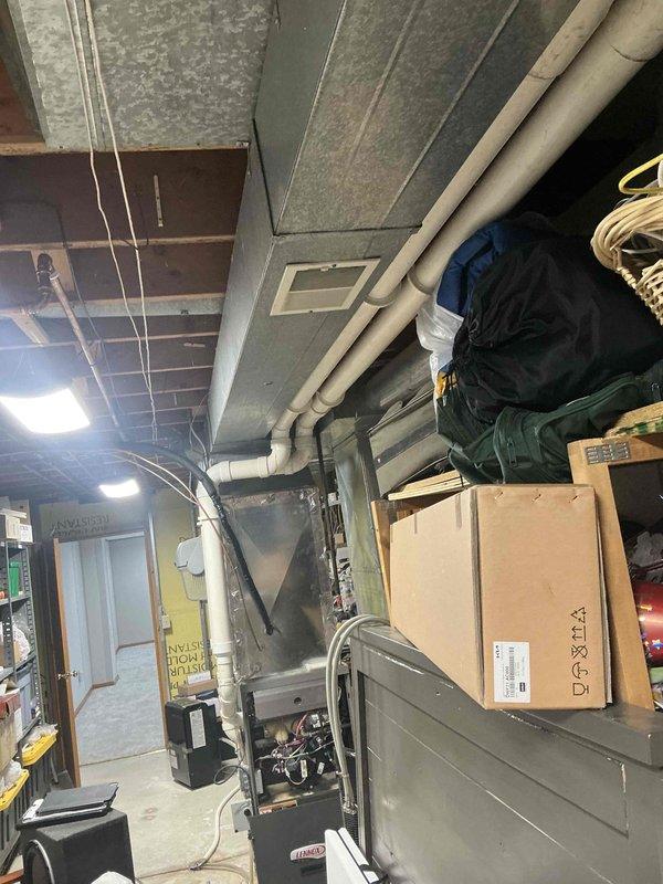 Conducted a thorough assessment of existing HVAC system in utility area. Documented furnace condition showing considerable wear with access panel removed for internal inspection. System features standard metal ductwork, PVC drainage pipes, and electrical connections that require upgrading. Recommended full replacement of the aging unit with a more efficient model to improve performance and reliability.