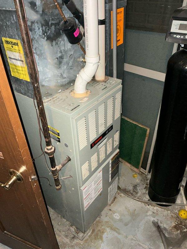 Completed inspection of basement HVAC system with focus on aging furnace unit and associated ventilation components. Documented existing installation including PVC exhaust configuration, water treatment system, and current structural integration within the utility space. Recommended full system replacement due to efficiency concerns and potential ventilation issues observed in the basement ceiling area.