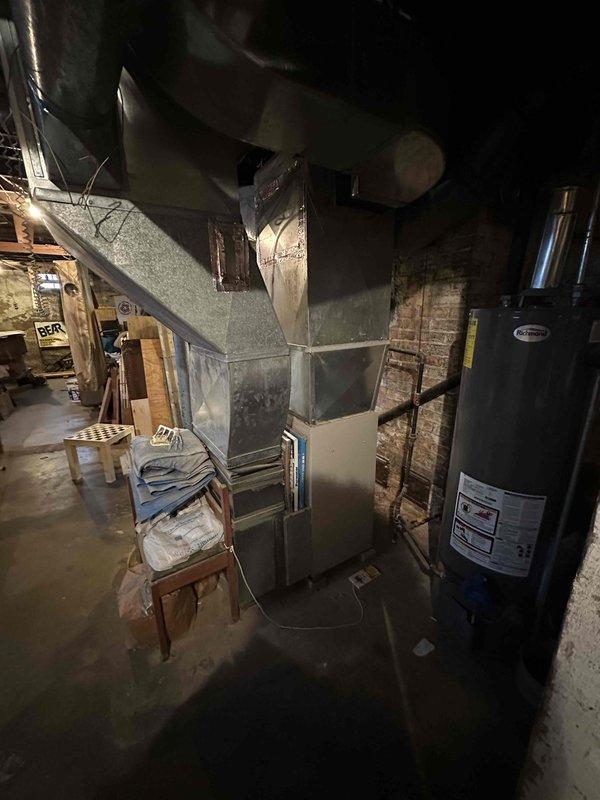 Conducted comprehensive assessment of existing HVAC system located in basement utility room, which includes an aging furnace with connecting metal ductwork and nearby water heater. Provided detailed replacement estimate for complete system upgrade based on observed condition of equipment and installation environment, noting exposed utility infrastructure and limited workspace considerations.