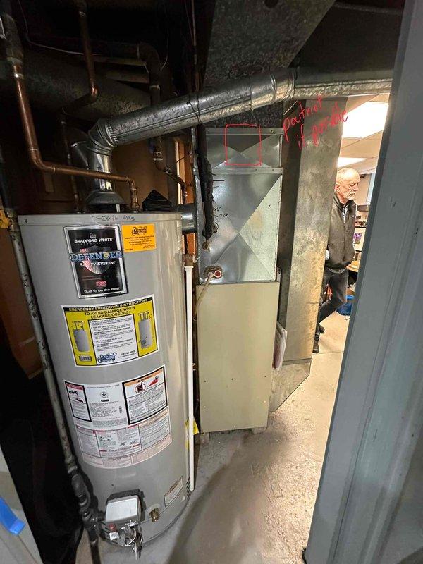 Conducted inspection of existing HVAC system in basement utility room, which includes a beige furnace unit connected to metal ductwork. Prepared replacement estimate for aging furnace system, documenting current configuration with adjacent water heater and existing ductwork infrastructure for proper sizing of new equipment.