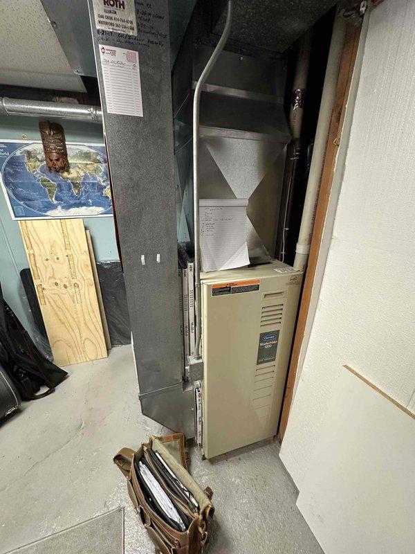 Conducted inspection of existing HVAC system in basement utility room, which includes a beige furnace unit connected to metal ductwork. Prepared replacement estimate for aging furnace system, documenting current configuration with adjacent water heater and existing ductwork infrastructure for proper sizing of new equipment.