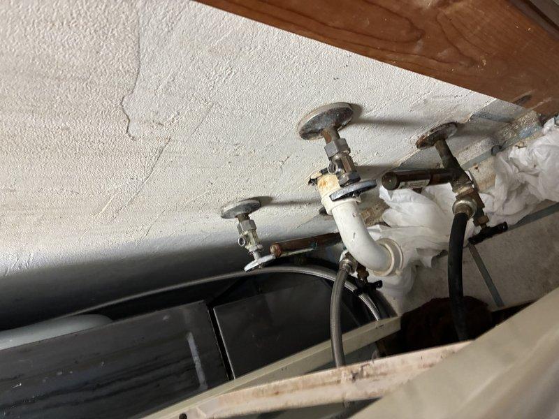 Inspected tank water heater installation with visible valves, supply lines, and connections. Observed normal wear on valve handles with some tarnishing. System appears functional with properly installed PVC piping, flexible braided supply lines, and appropriate shut-off valves all in working condition.