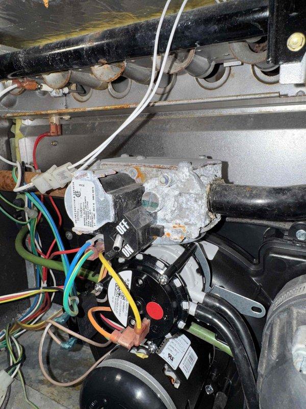 Performed routine commercial tune-up on HVAC system. Noted significant mineral buildup and corrosion around valve connections on heat exchanger pipes. Cleaned accessible components and inspected electrical connections, observing proper wire terminations at motor assembly. System operational but recommend follow-up service to address progressive corrosion issues on heat exchange components.