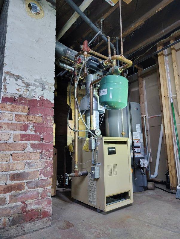 Responded to no heat complaint for residential hydronic heating system. Diagnosed faulty expansion tank and failing valve assembly. Replaced green expansion tank and red valve assembly, bled air from system, and verified proper heat circulation and pressure to restore full functionality.