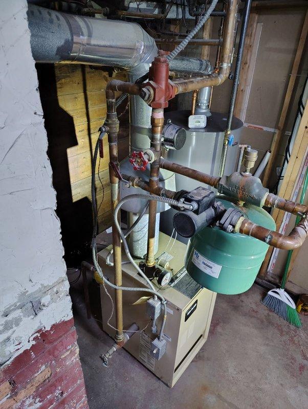 Responded to no heat complaint for residential hydronic heating system. Diagnosed faulty expansion tank and failing valve assembly. Replaced green expansion tank and red valve assembly, bled air from system, and verified proper heat circulation and pressure to restore full functionality.