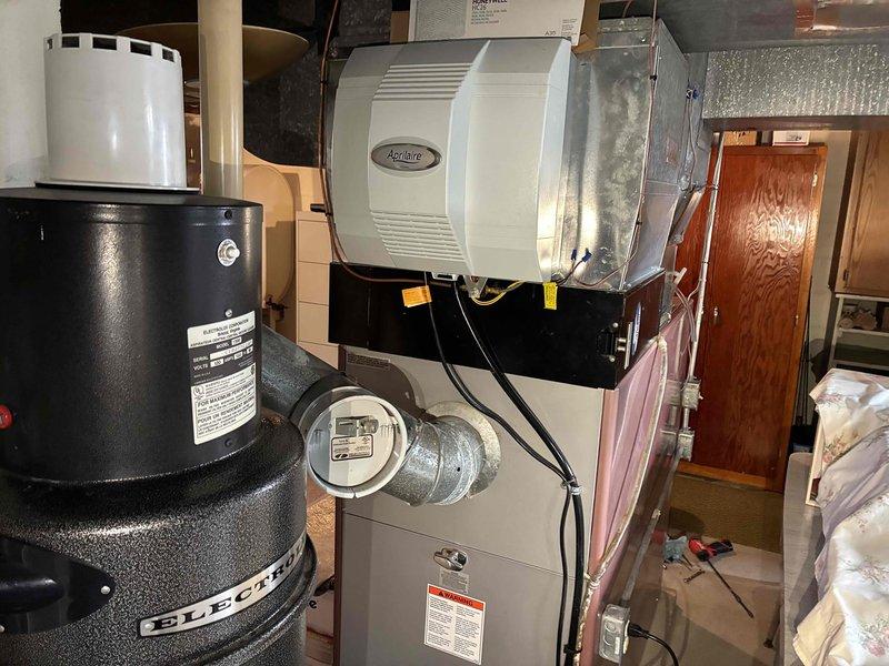 Completed tune-up service on HVAC system with focus on the Aprilaire humidifier unit mounted on ductwork. Inspected and cleaned humidifier components, checked water panel for mineral buildup, verified proper drainage and water supply. Examined adjacent ductwork insulation integrity and connections, ensuring proper airflow throughout the system.